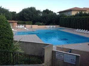 A swimming pool with white lounge chairs and a sign indicating a reserved pool for residents.