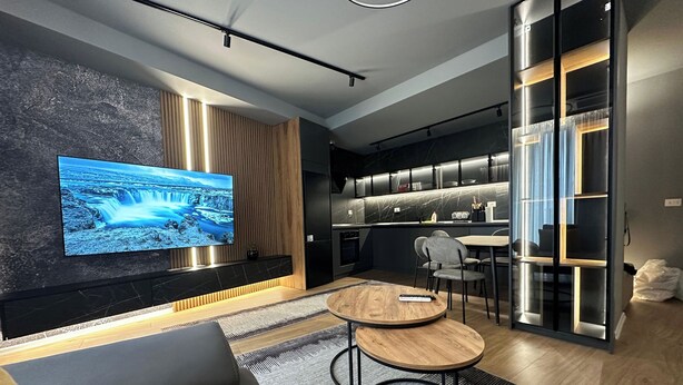 Un salon moderne avec un téléviseur, un canapé et un coin repas comprenant des chaises et une table.