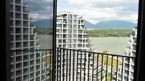 Un immeuble de grande hauteur doté de nombreux balcons, offrant une vue sur un plan d’eau et des montagnes.