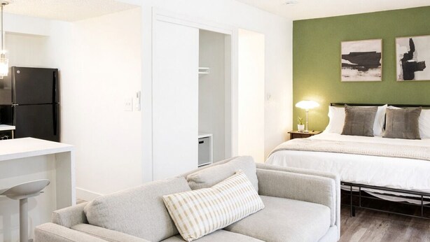 Een moderne slaapkamer met een bed, een bank, een bureau en een koelkast.