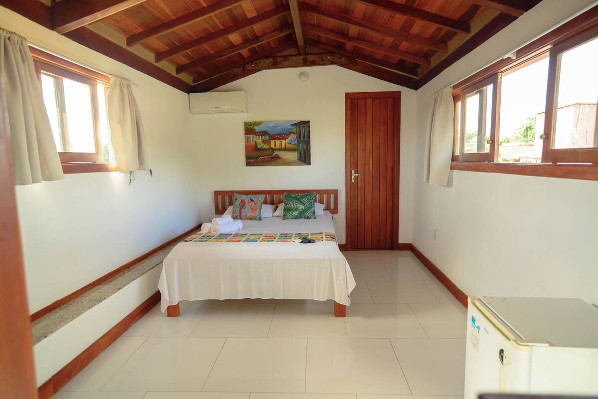 A bedroom with a bed, a painting on the wall, and a door.