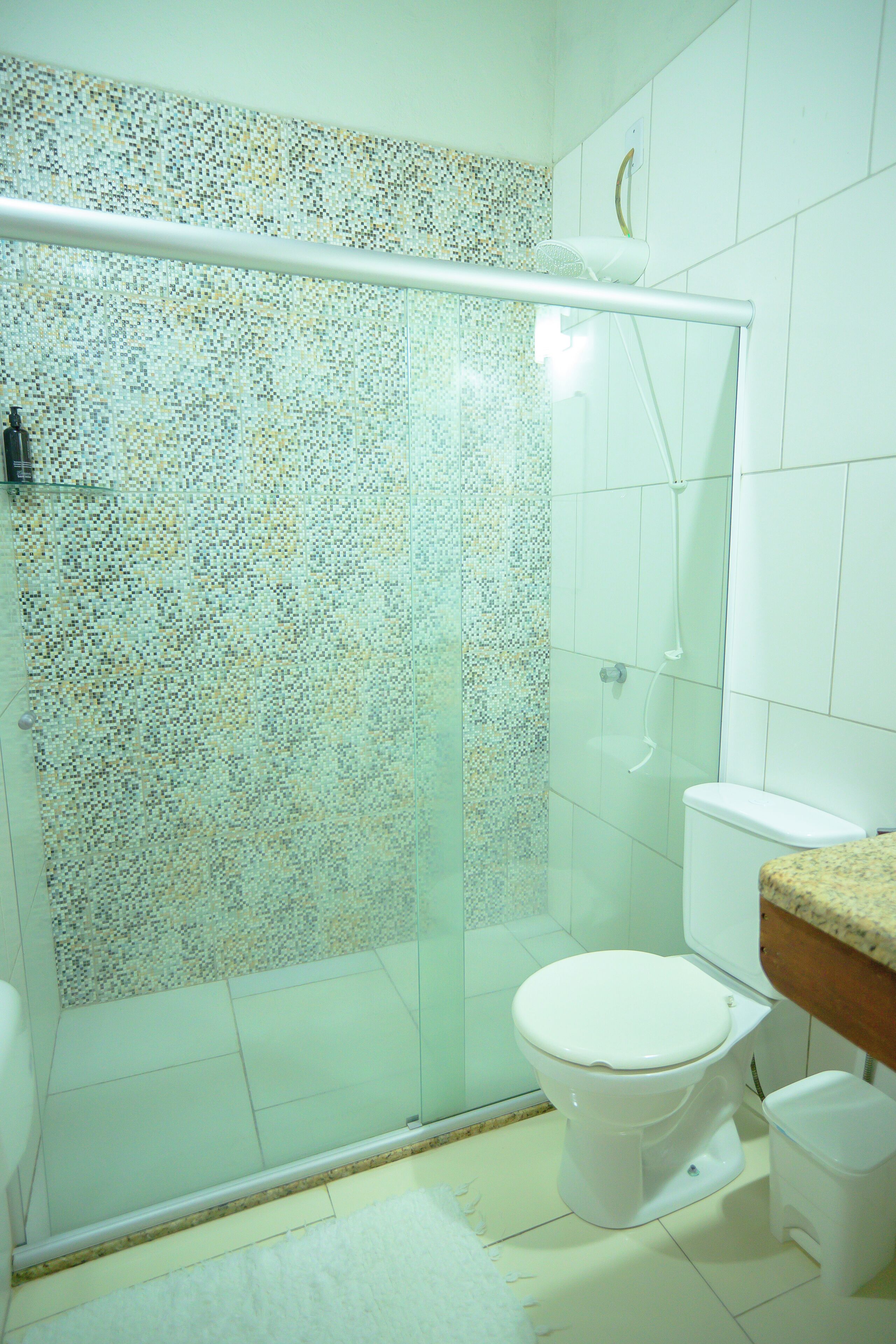 A bathroom with a shower enclosure, toilet, and a sink.
