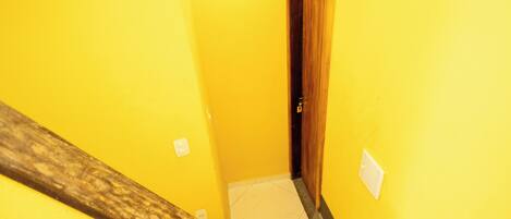 A narrow hallway with yellow walls, a wooden door, and a tiled floor.