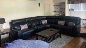 A living room with a black leather sectional sofa, a glass coffee table, and a patterned rug. - Spacious Waterfront in the French River

 (Noëlville)