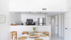 A modern kitchen with white cabinets, stainless steel appliances, and a dining area with a round table and stools. - Condo in Vero Beach, Florida  a view of the Marina just outside your Window (Vero Beach)