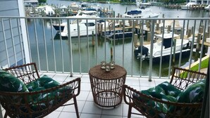 A balcony with wicker chairs and a small round table, overlooking a marina with boats docked. - Condo in Vero Beach, Florida  a view of the Marina just outside your Window (Vero Beach)