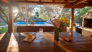 A wooden table with a glass of white wine, a cutting board with a knife, and a vase with flowers. - Holiday home Maša with heated pool- near NP Krka/ RENEWED, NEW PHOTOS SOON (Ljubotic)