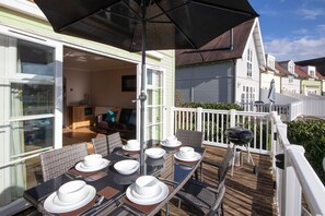 Ein Außenbereich zum Essen mit Tischen, Stühlen, einem Grill und Blick auf die Nachbarschaft.