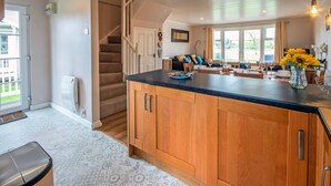 A spacious kitchen with a large island, wooden cabinets, and a view of the living area through an open door. - Isis Lakes 50, Natterjack Lodge - Lakeside Lodge, On-Site Activities, Sleeps 6 (SOUTH CERNEY)