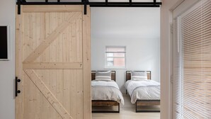 A room with two beds, a wooden door, and a window with blinds. - Fall Line- Curate Telluride,Hot Tub,Remodeled, Walk to Ski, Center of Town, Park (Telluride)