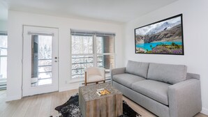 A modern living room with a grey sofa, a wooden coffee table, and a large landscape painting on the wall. - Fall Line- Curate Telluride,Hot Tub,Remodeled, Walk to Ski, Center of Town, Park (Telluride)