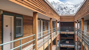 A corridor with wooden walls and metal railings, leading to a staircase with a view of snow-covered mountains. - Fall Line- Curate Telluride,Hot Tub,Remodeled, Walk to Ski, Center of Town, Park (Telluride)