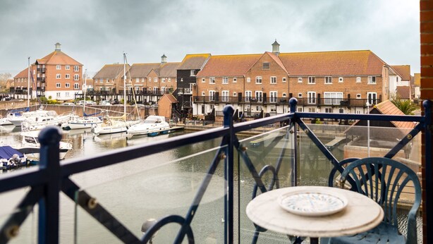 Une vue depuis un balcon donnant sur une marina, avec des bateaux, un canal et des maisons à étages.