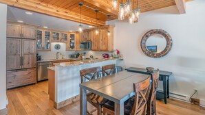 A kitchen with wooden cabinets, a central island with seating, and pendant lighting.