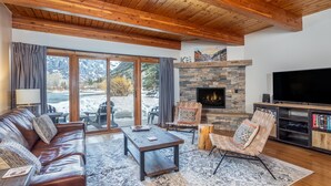 A cozy living room with a stone fireplace, leather sofa, and a flat-screen TV.