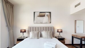 A modern hotel room with a large bed, two bedside tables with lamps, a headboard, and a painting on the wall. - 605 Turia BlockA, The Greens (The Greens)