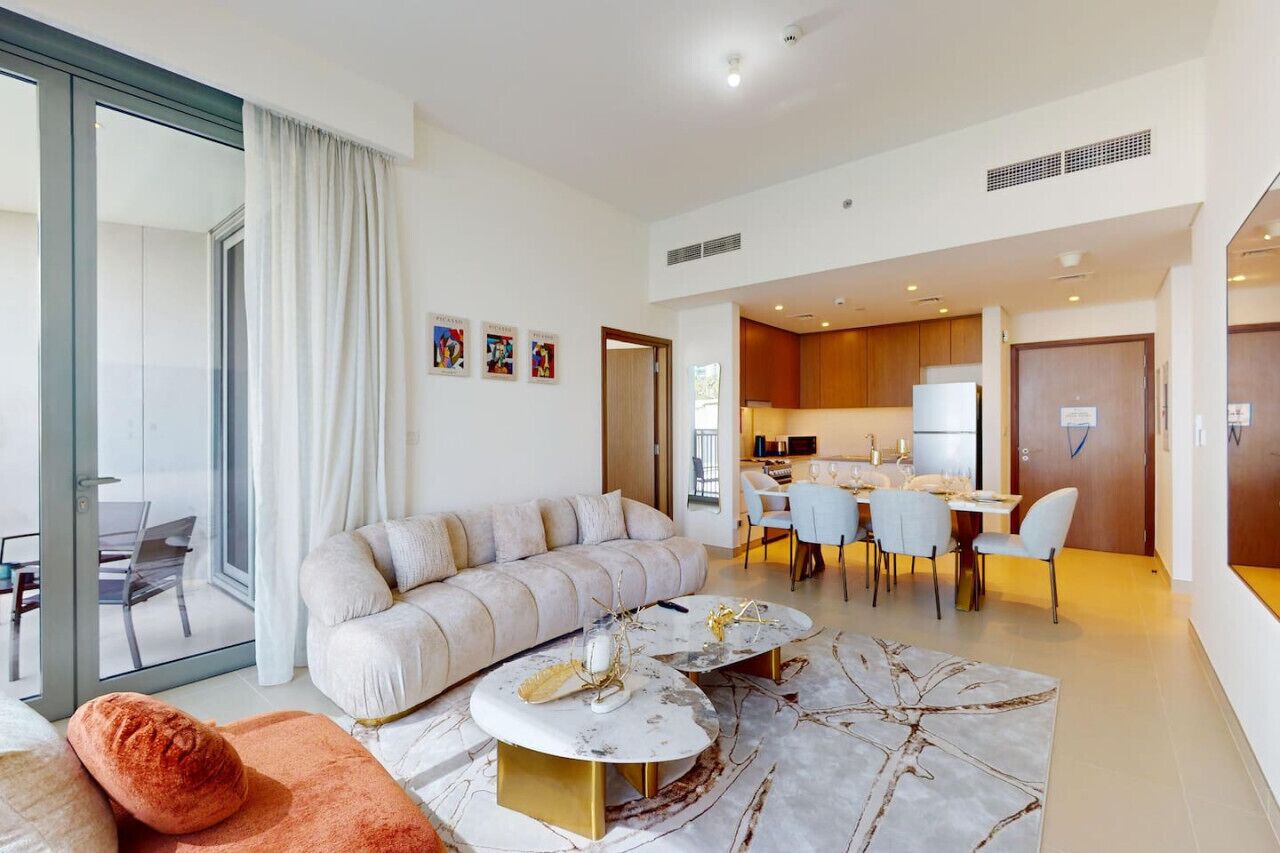 A modern living room with a sofa, two coffee tables, and a dining area with chairs.