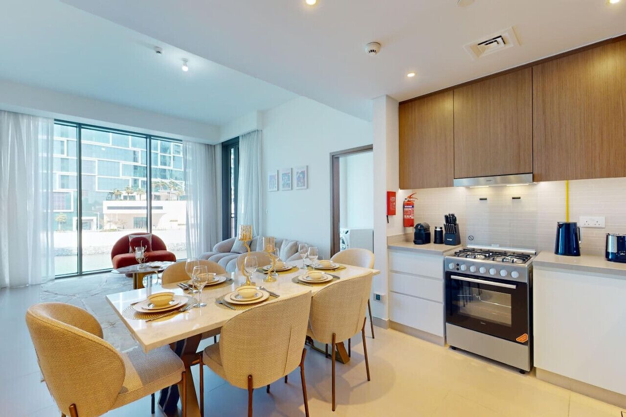 Een moderne keuken met een gasfornuis, witte kasten en een eethoek met een tafel gedekt voor vier personen.