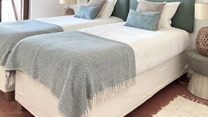 A double bed with a green headboard, two bedside tables, and a woven throw blanket. - Casa da Praia (Colares)