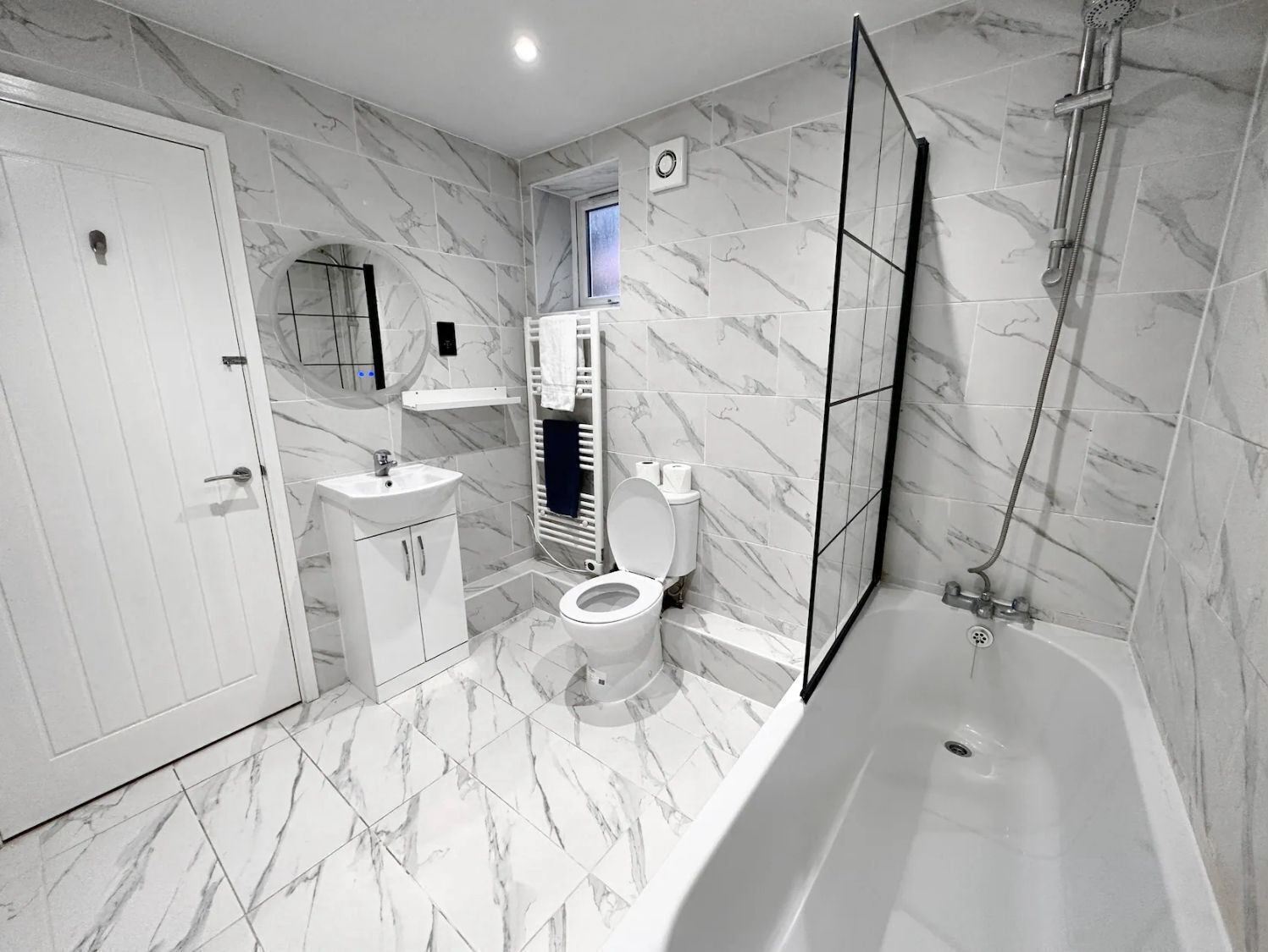 Une salle de bain moderne équipée d’une baignoire, de toilettes, d’un lavabo et d’une cabine de douche.
