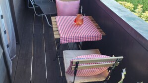A balcony with two tables, each covered with a red and white checkered tablecloth, and two chairs. - Stilvolle Ferienwohnung im Ortszentrum, Ruhig Gelegen (Grassau)