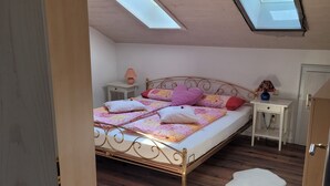 A bedroom with a bed, a nightstand, a lamp, a door, and a skylight. - Stilvolle Ferienwohnung im Ortszentrum, Ruhig Gelegen (Grassau)