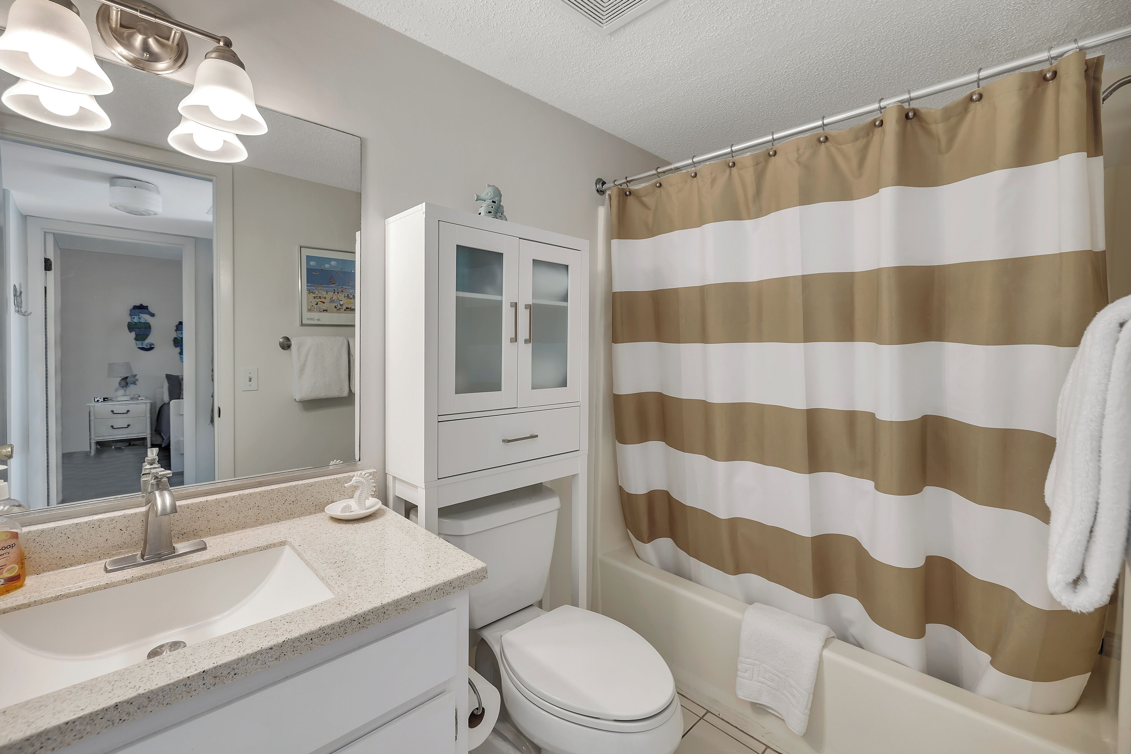 A bathroom with a white sink, a toilet, a cabinet, and a shower curtain.