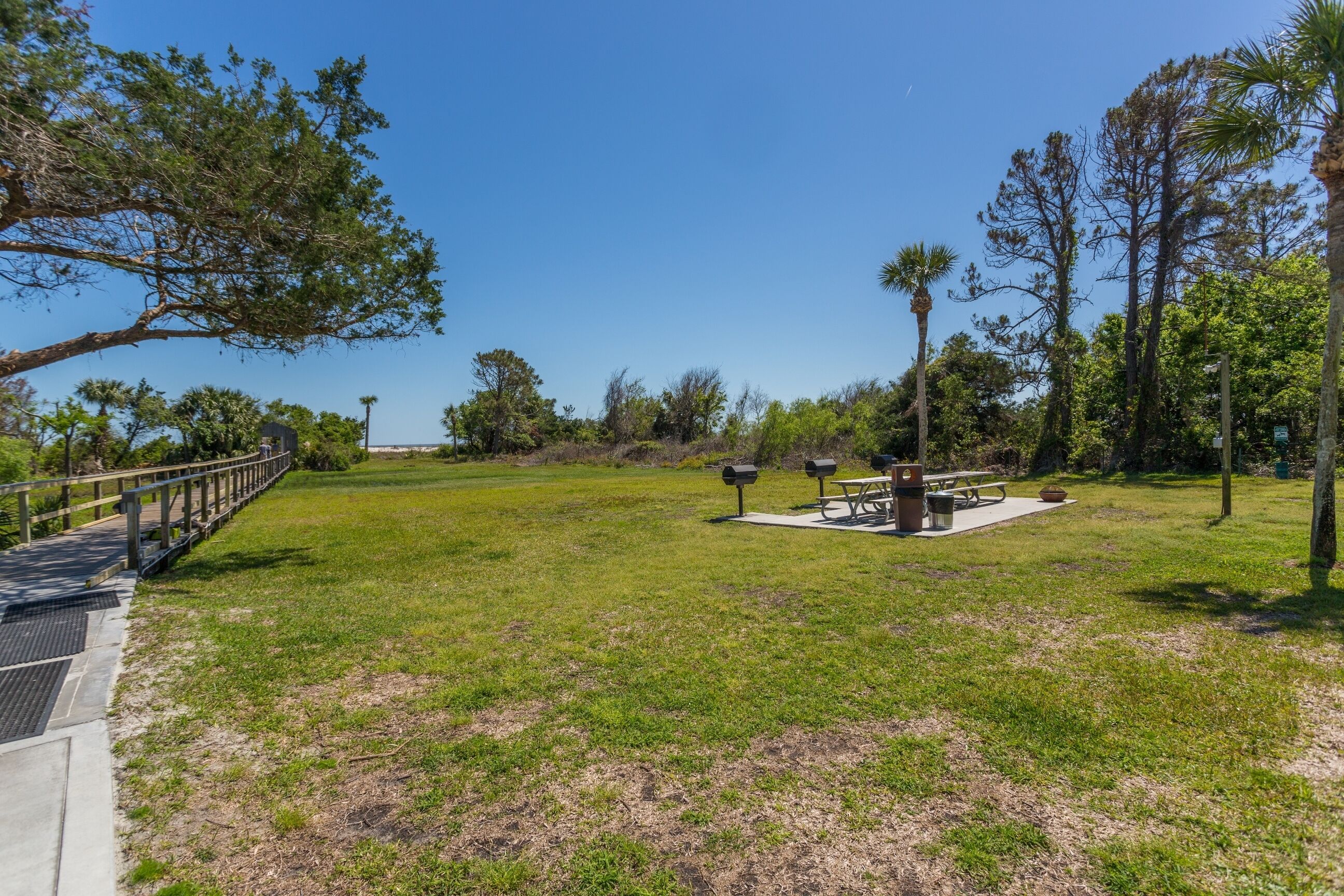 A park with a picnic area, benches, and a wooden bridge.