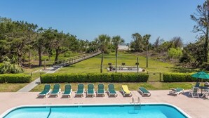 Una piscina con sillones de descanso, un sendero peatonal y vistas a un campo de golf.
