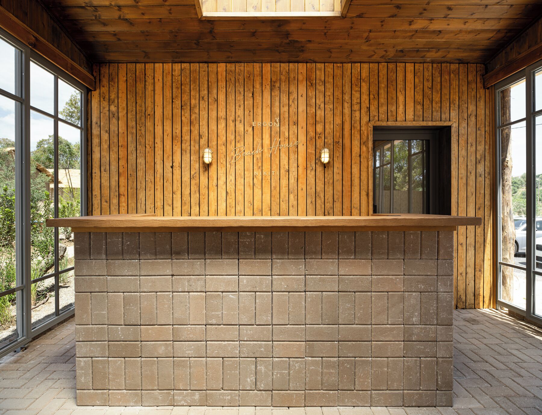A wooden reception desk with a brick base, large windows, and a door.