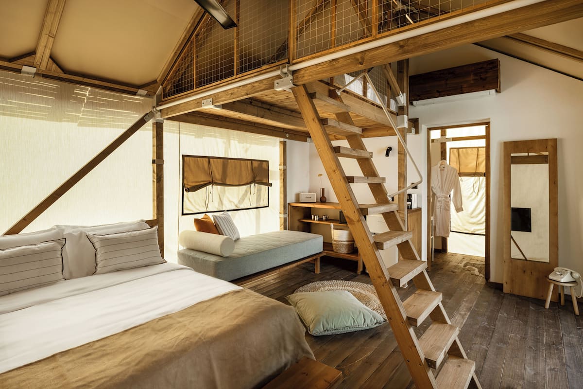 Ein Schlafzimmer mit Etagenbett, einer Schlafcouch, einem Schreibtisch und einer Treppe.