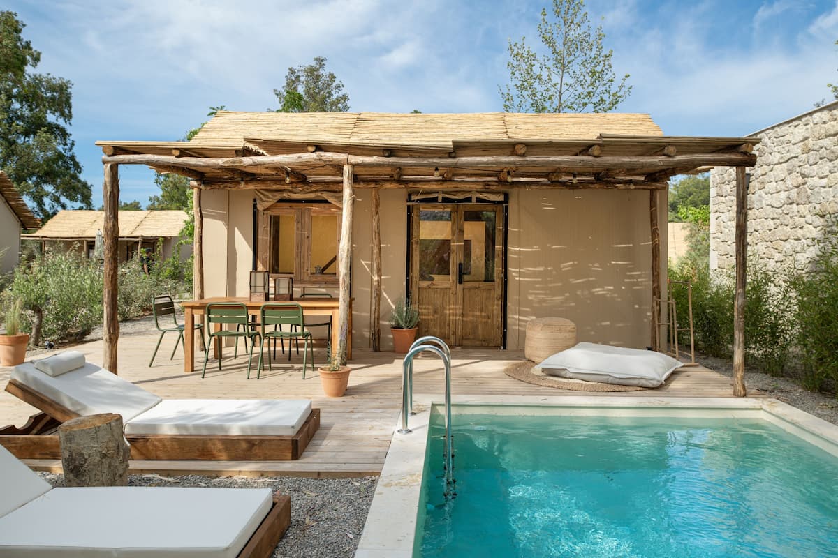 Ein Poolbereich mit Pergola, Liegestühlen, einem Tisch und einem kleinen Pool.