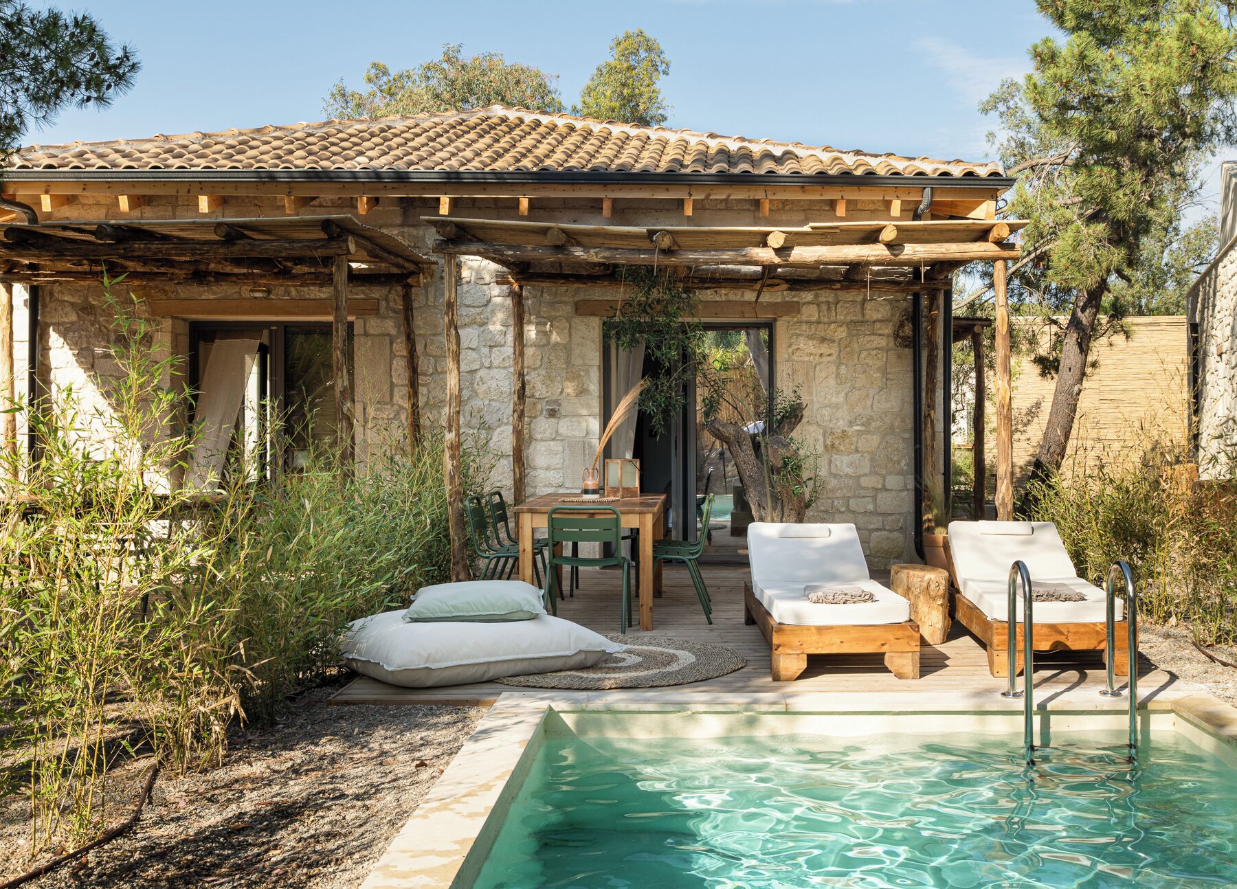 Un espace aménagé au bord de la piscine, comprenant une pergola, des chaises longues et une table avec des chaises.