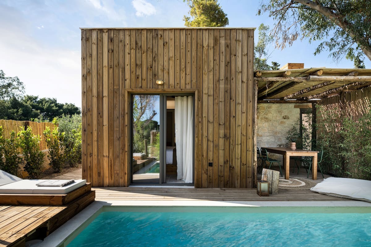 Eine Holzhütte mit Pool, Essbereich und einer Pergola.