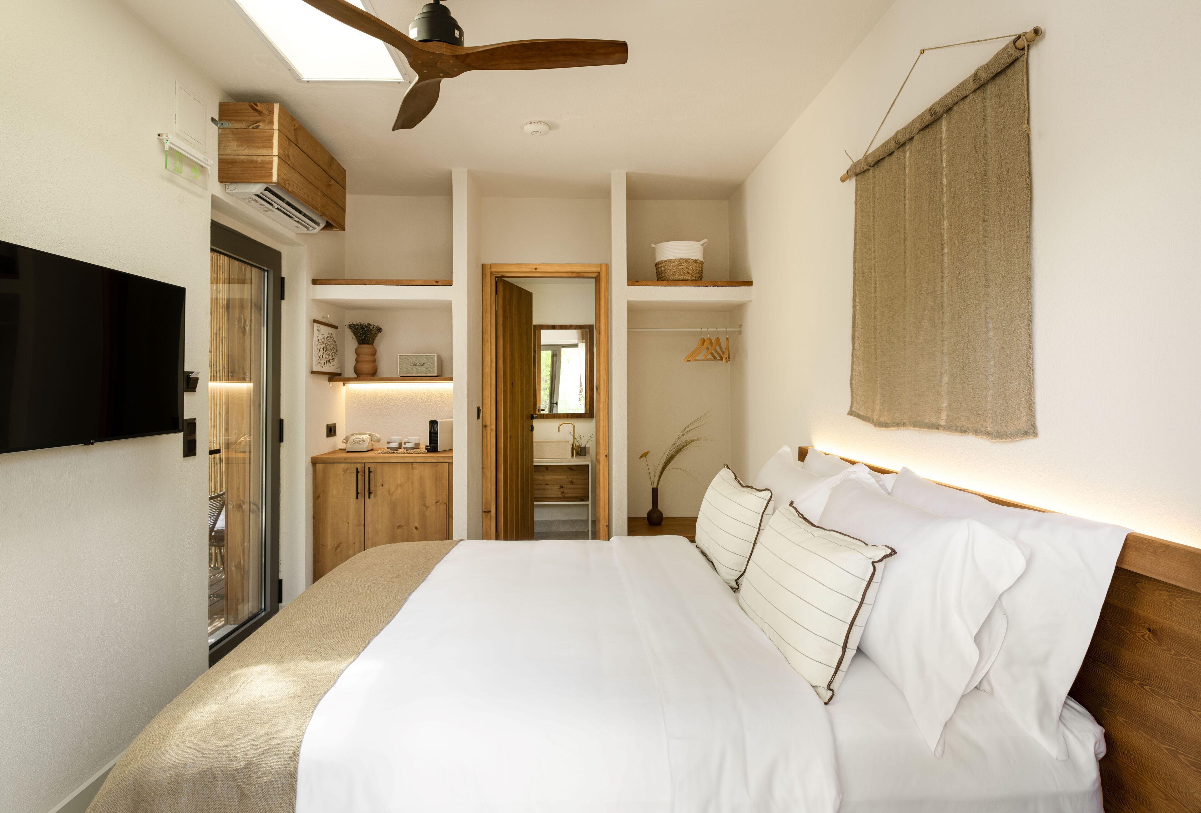 Ein Schlafzimmer mit einem großen Bett, einem Holzkopfende, einem Deckenventilator, einem Fernseher und einem Kleiderschrank.