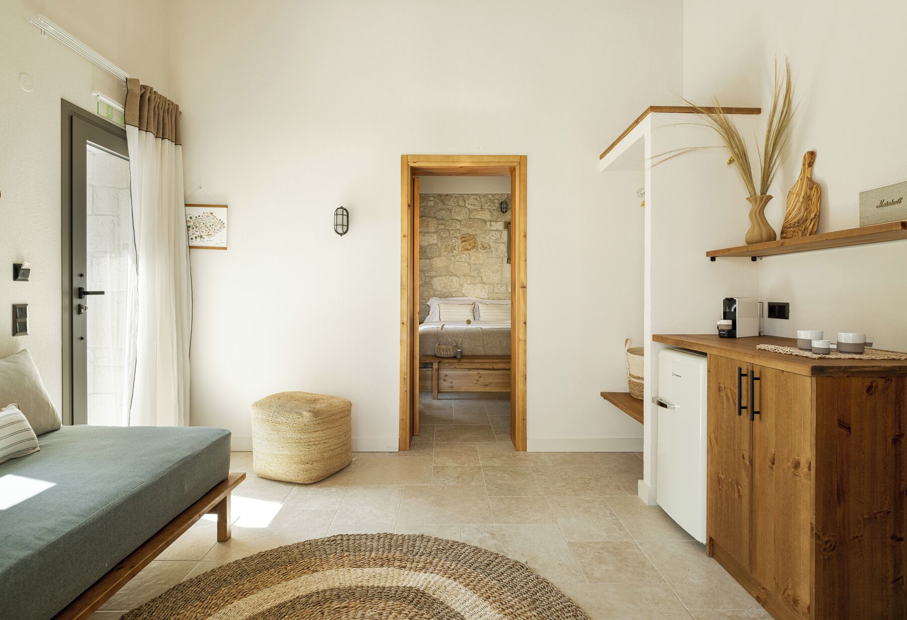 A bedroom with a bed, a bedside table, a lamp, and a view into the adjacent bathroom.