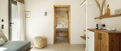 A bedroom with a bed, a bedside table, a lamp, and a view into the adjacent bathroom.