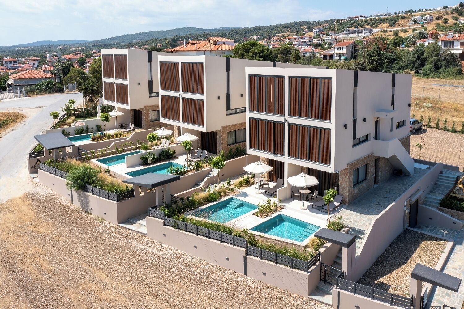 Un moderno edificio de varios pisos con una zona de piscina en la azotea, múltiples piscinas y mobiliario de exterior.