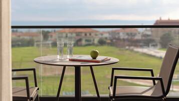 Un balcón con una mesa redonda, dos sillas, un libro y una manzana verde.