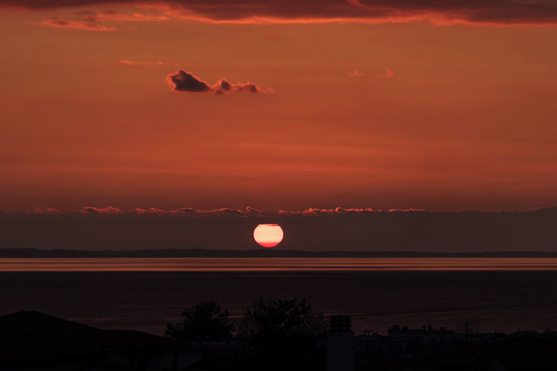 Un atardecer sobre una masa de agua con el perfil de un paisaje urbano al frente.
