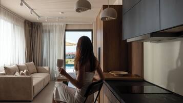 Een moderne keuken met uitzicht op een zwembad, een zithoek met een bank, en een persoon met een glas.