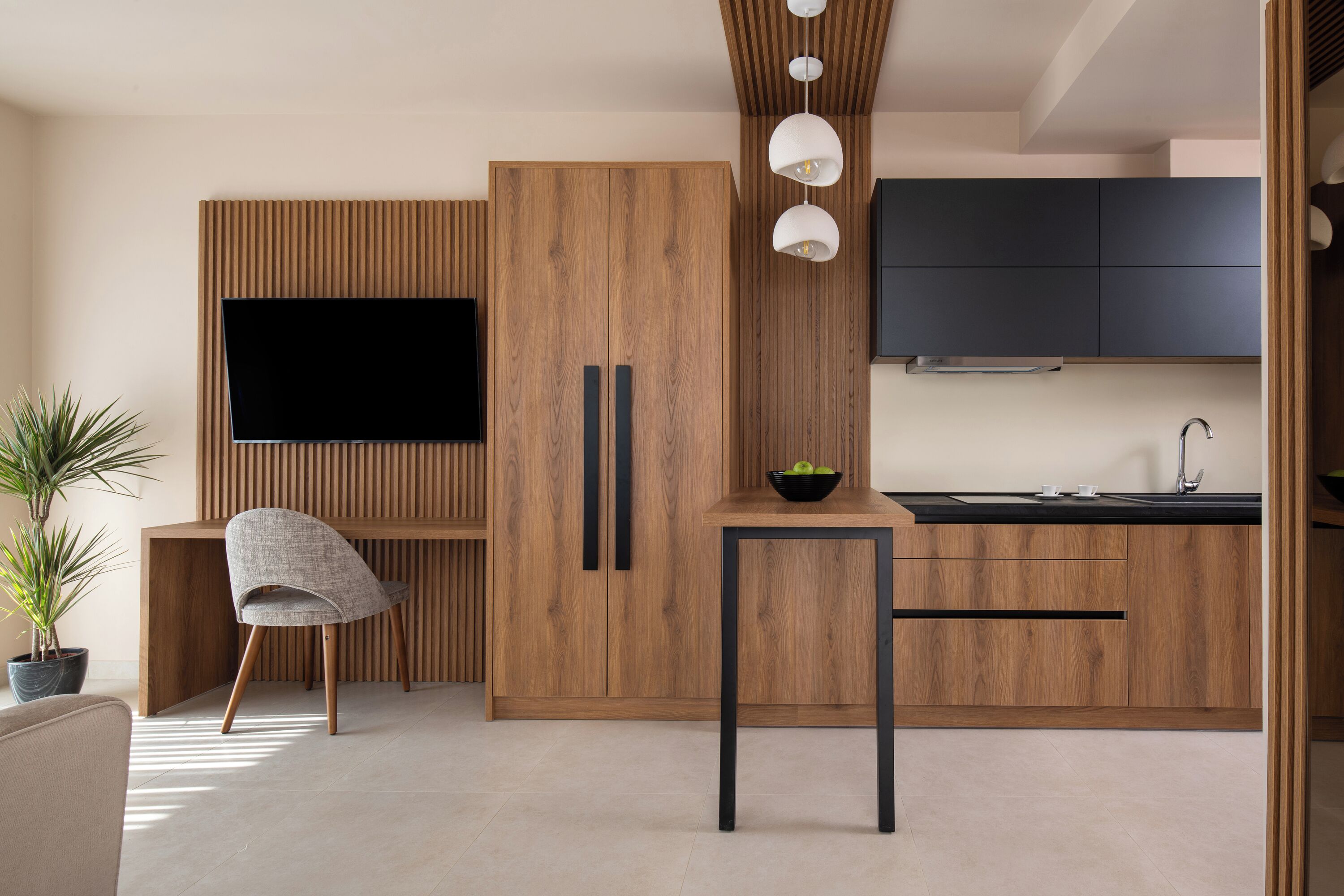 Una cucina moderna con mobili in legno, un piano di lavoro nero e una TV integrata.