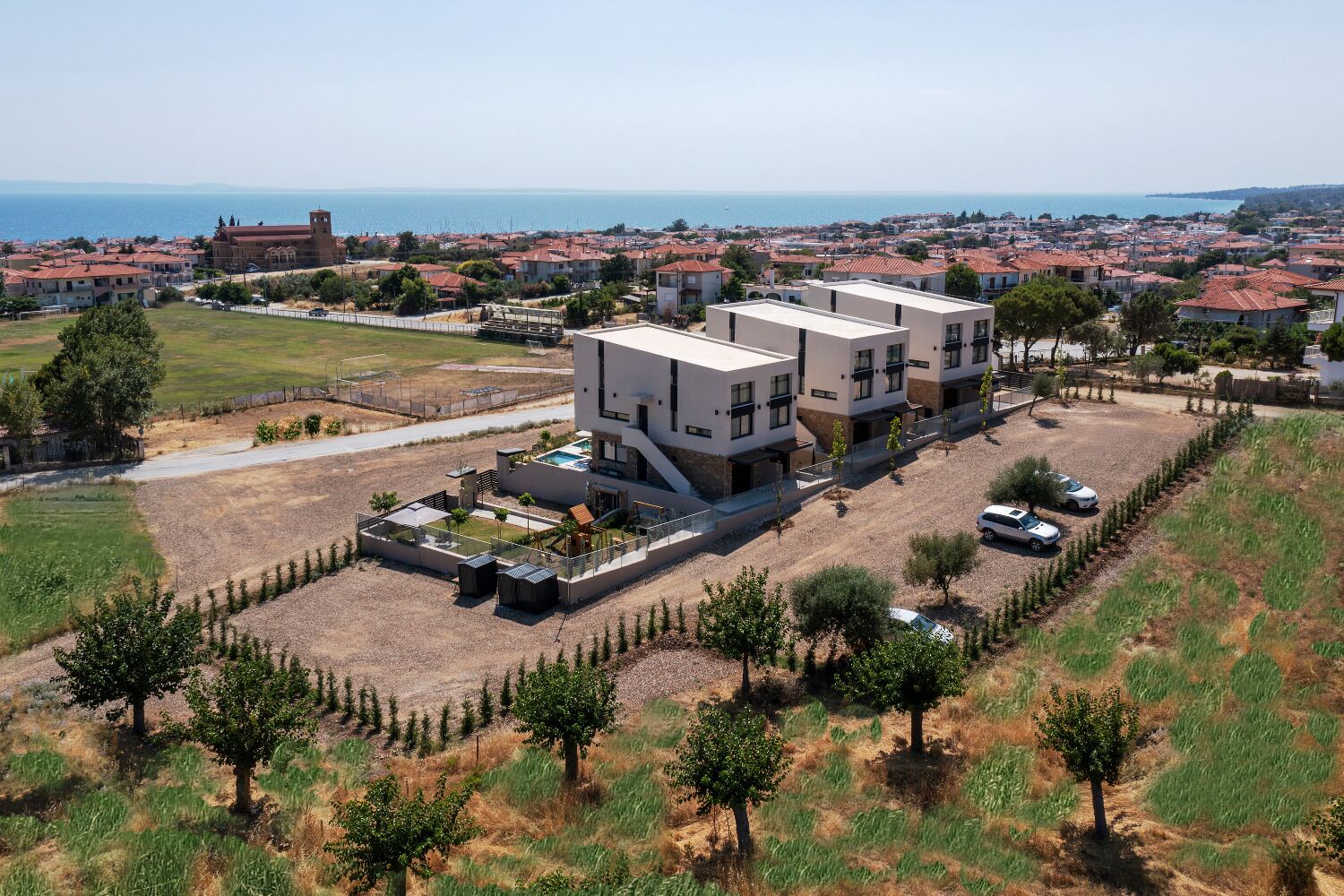 Una casa moderna de dos pisos con piscina, rodeada de un jardín ajardinado y vista al mar.