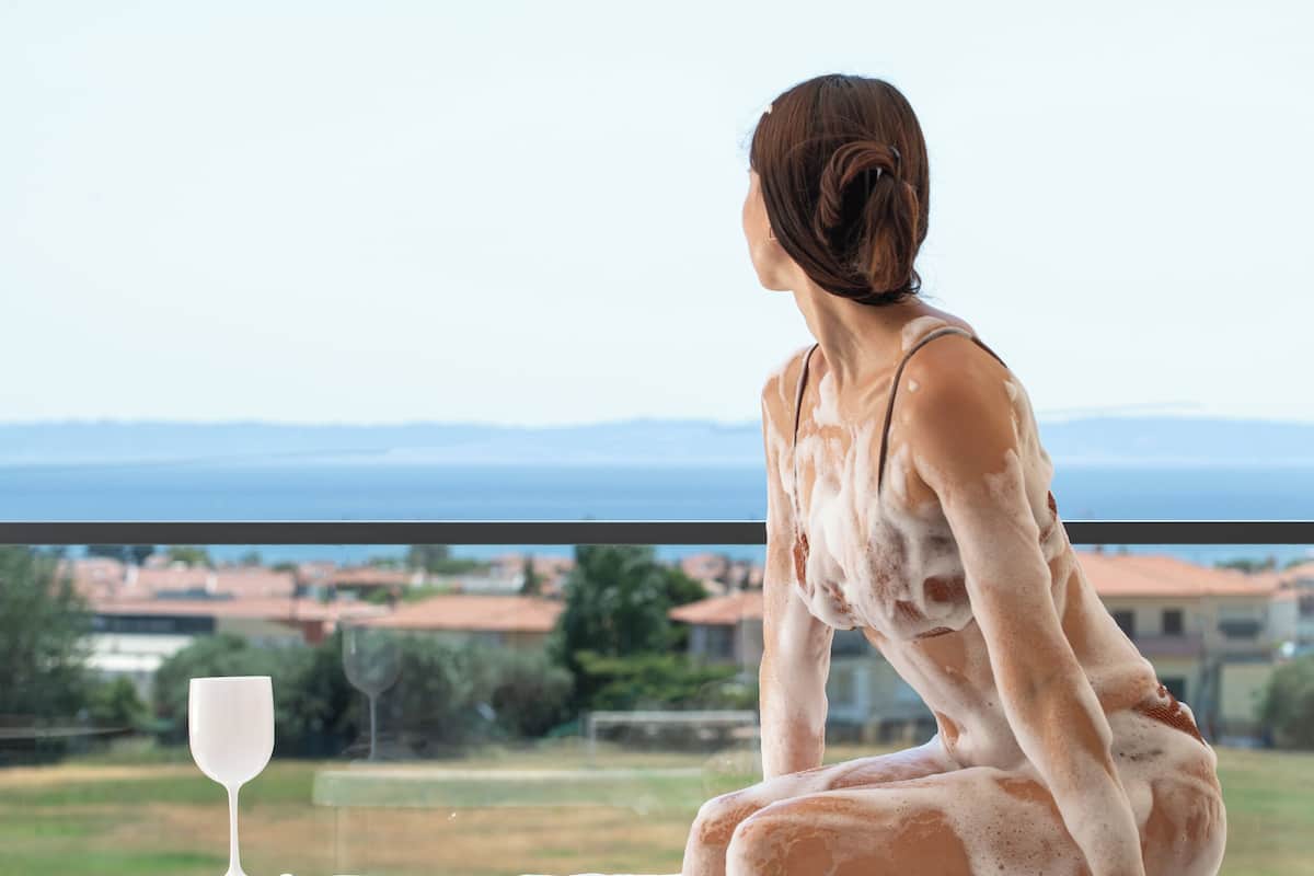 Uma pessoa sentada em uma banheira com vista para uma paisagem.