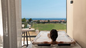 A person relaxing on a massage table with a view of a grassy area and buildings in the distance. - Anore Luxury Suites  (Sithonia)