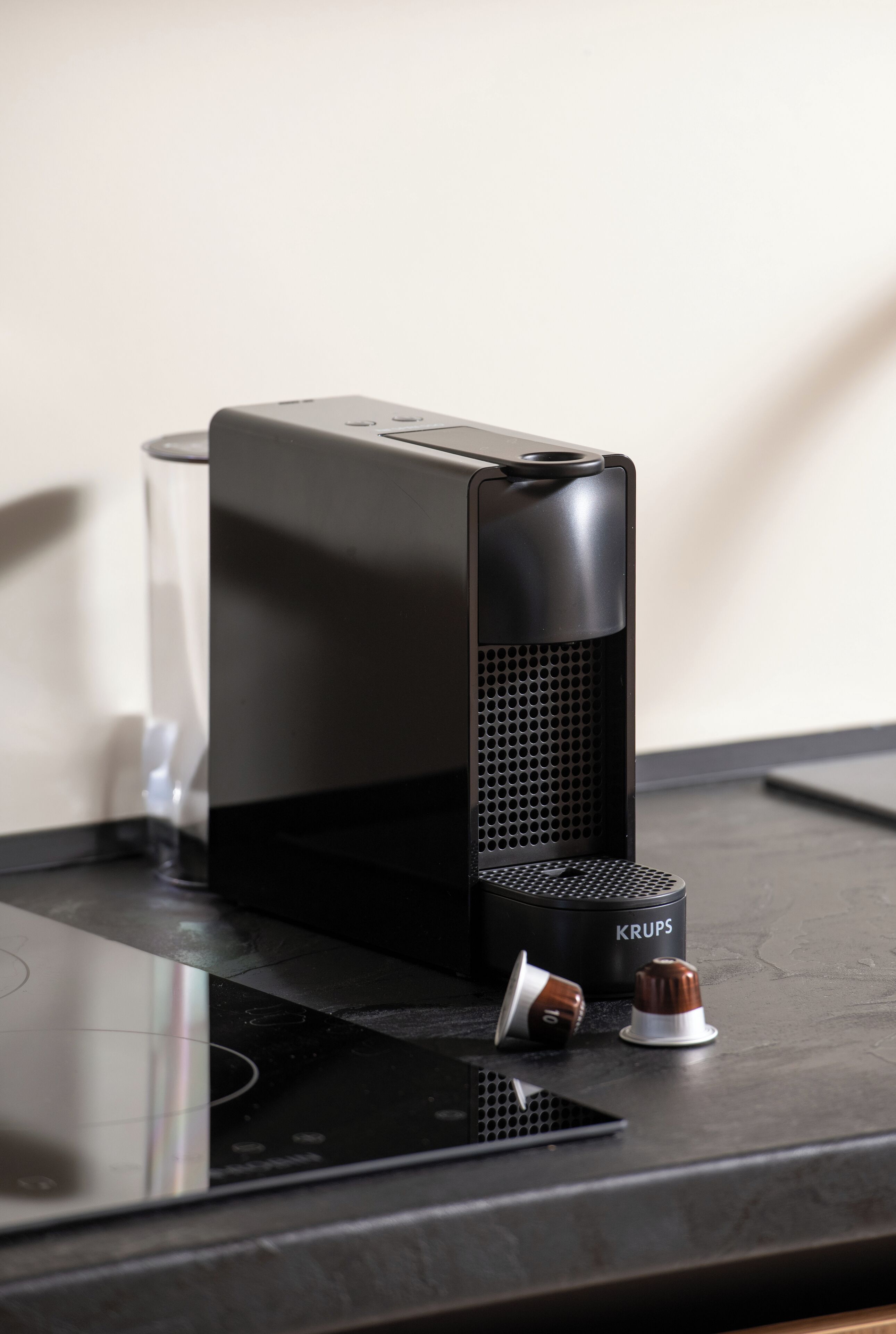 A coffee machine with a Krups brand logo on a black countertop.