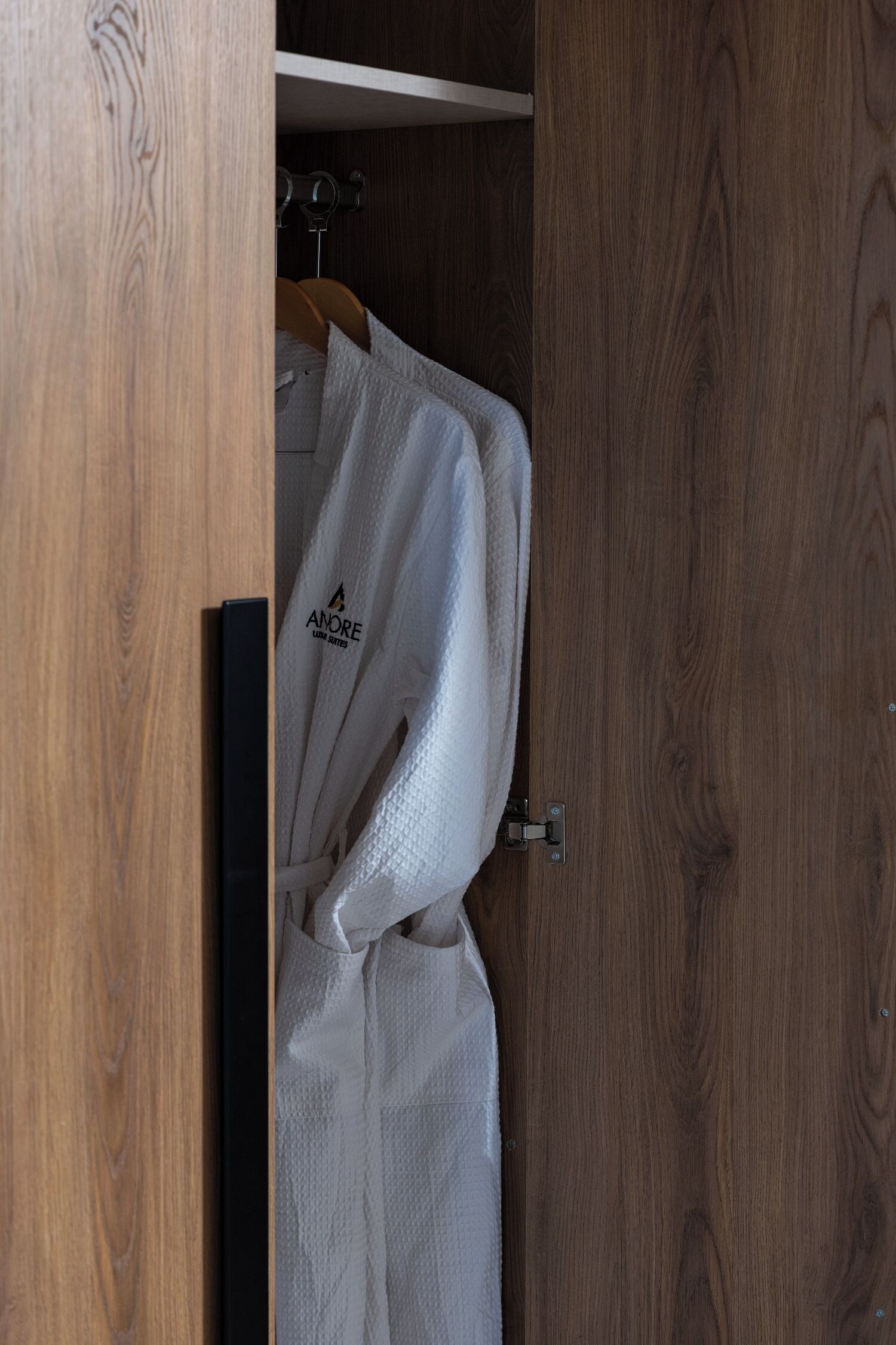 A wooden wardrobe with a hanging robe labeled "ANORE LUXURY SASHES."