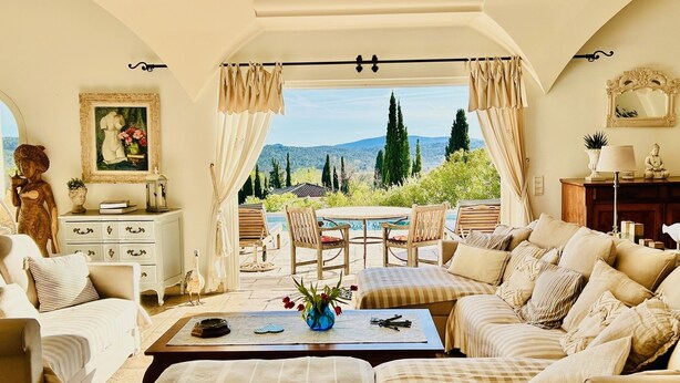 Ein gemütliches Wohnzimmer mit Bergblick, eine Essecke mit Tisch und Stühlen sowie eine Sitzecke mit Sofas und einem Couchtisch.