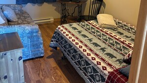 Une chambre à coucher de taille modeste, comprenant un lit, un téléviseur, un ventilateur de plafond et une petite table.