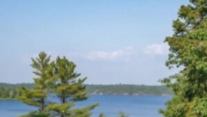 Une vue sur le lac, avec une zone herbeuse, des arbres et une jetée qui s’avance dans l’eau.